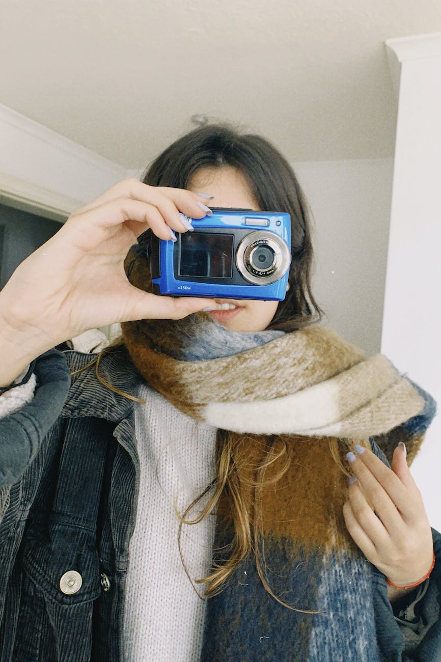 a female holding an analog camera in her face